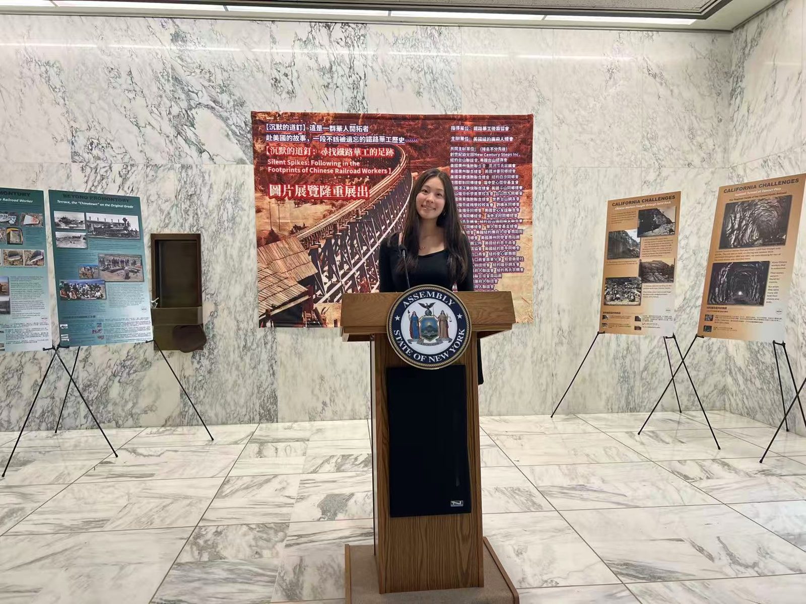 Joy at a New York State Assembly podium in front of the Chinese railroad workers exhibition in Albany